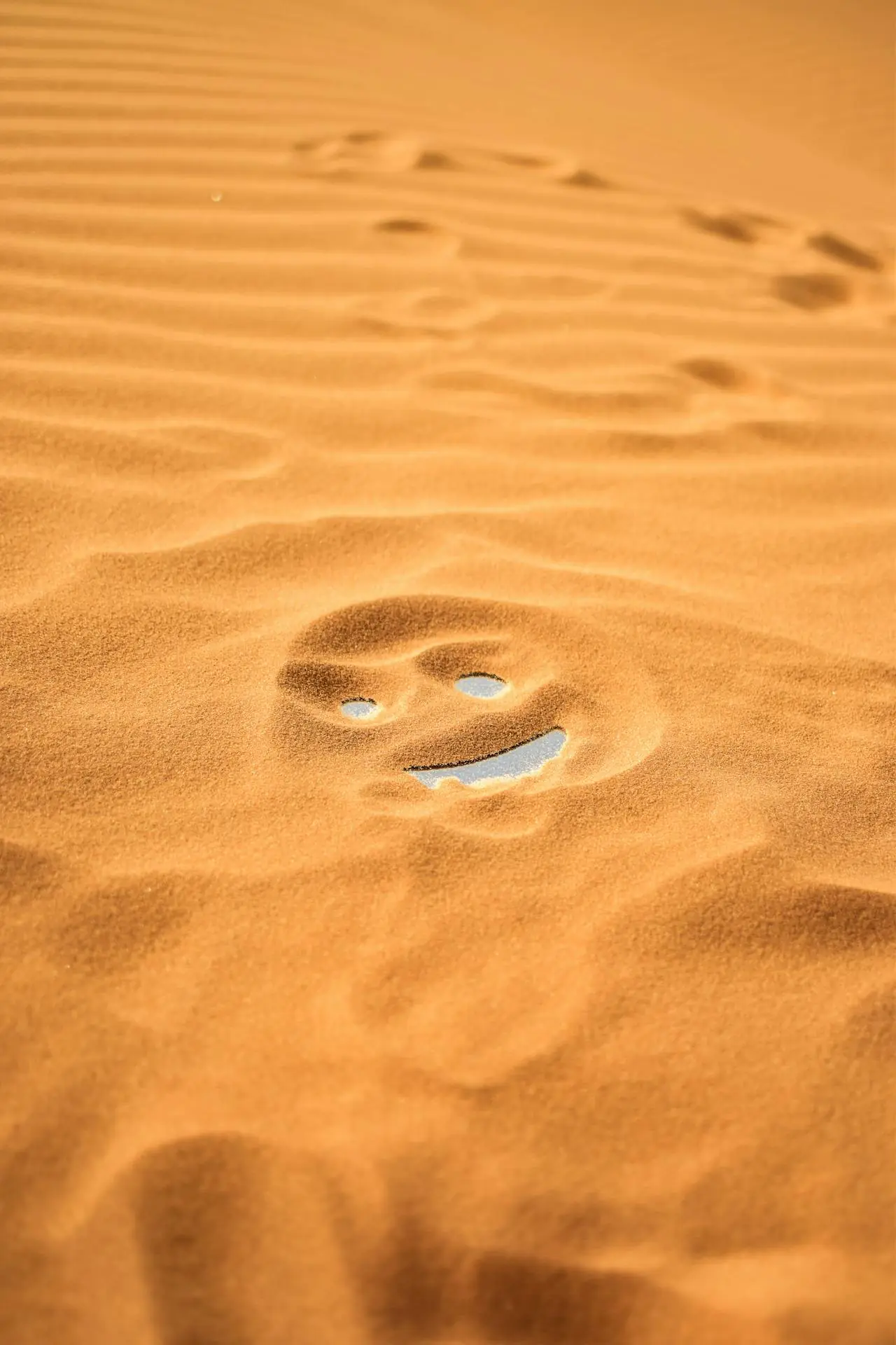 Sand einer Wüste, in dem ein Gesicht auf dem Boden zu erkennen ist.