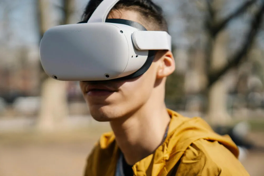 Junger Mann trägt eine VR-Brille im Freien. Im Hintergrund Bäume.